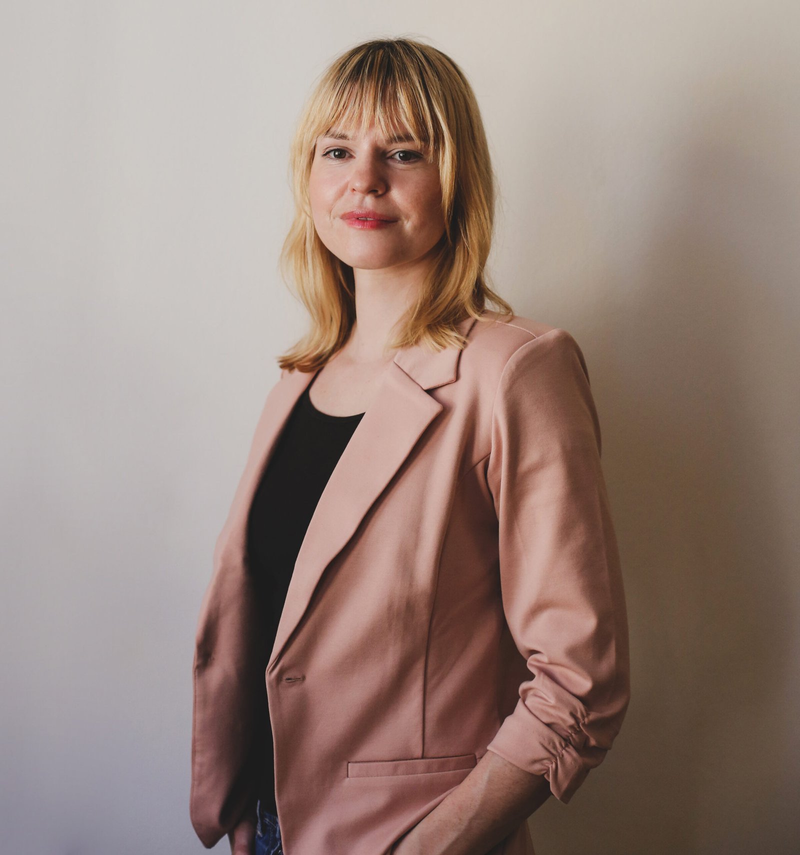 Regina steht selbstbewusst und professionell vor neutralem Hintergrund - erfahrene Doula und Geburtsbegleiterin