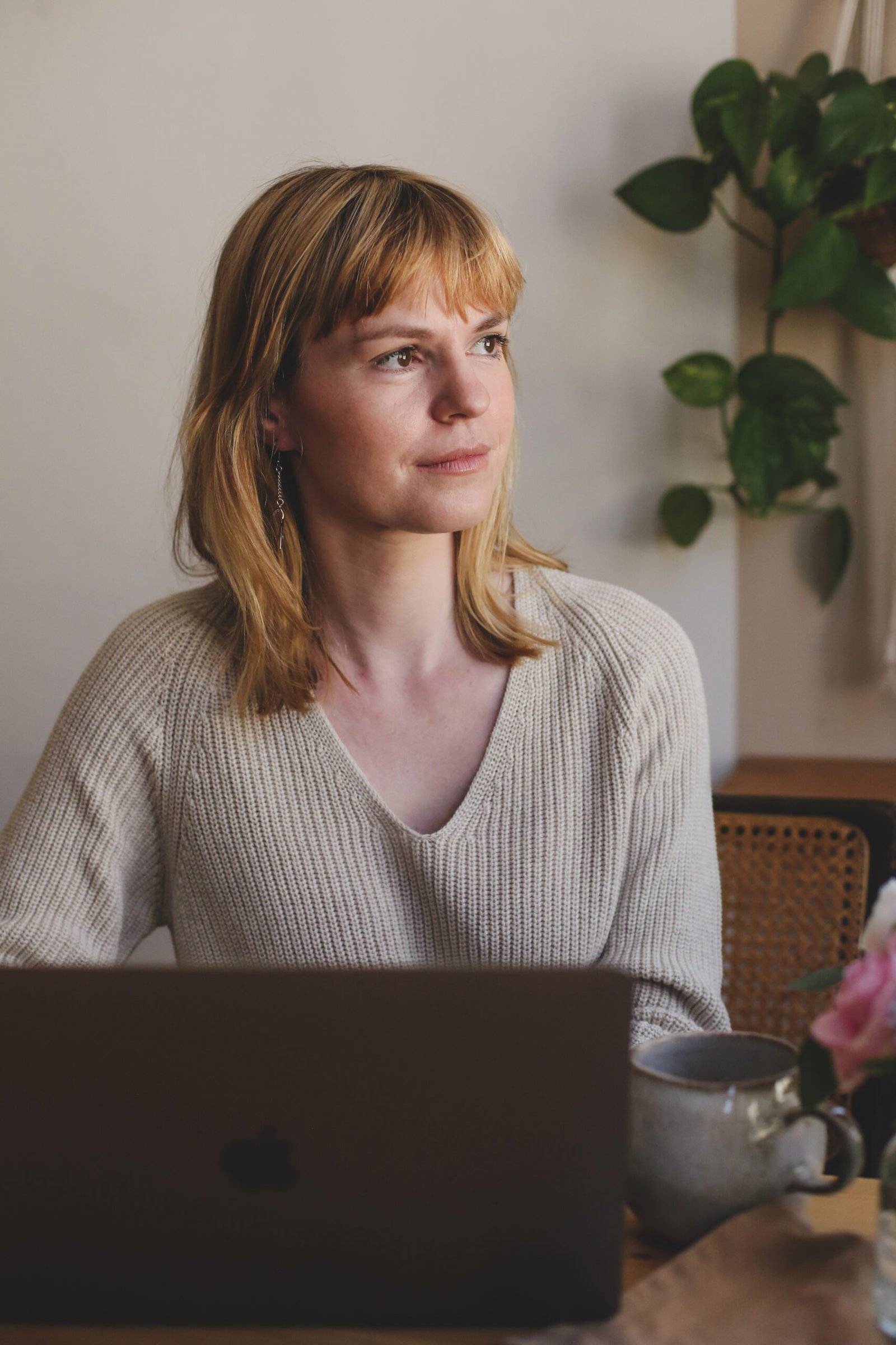 Regina sitzt entspannt am Laptop und schaut nachdenklich zur Seite - bereit für dein Kennenlerngespräch<br />
